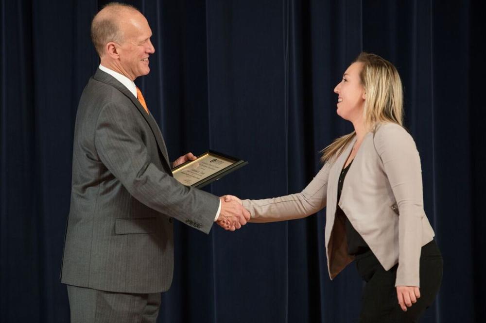 Doctor Potteiger shaking hands with an award recipient in a beige cardigan